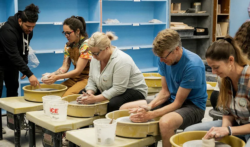photo of adult students working with handbuilding clay led by instructor